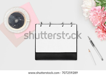 Workspace on white background. Three pink white peonies, cup of coffee, day planner, pen and white pencil. Flat lay. Business woman background. Place for text
