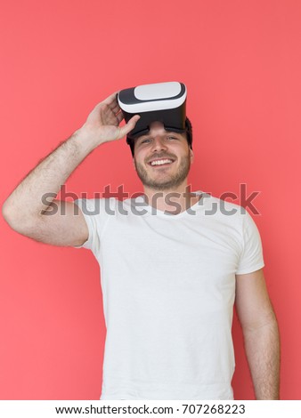 Happy man getting experience using VR headset glasses of virtual reality, isolated on red background