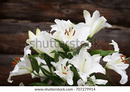 White lilies on brown wooden background