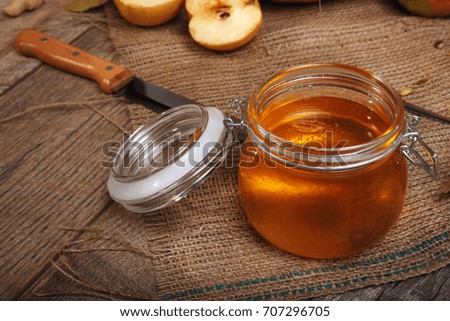 A close-up picture of a bright autumn candied fruit jelly next to orange vegetables full of vitamins and a knife on a wooden table background. Sweet honey on a rustic napkin. Autumn harvest.