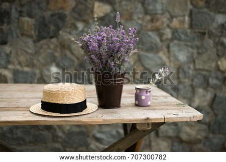 flowers of purple lavender in a pot and retro canotier straw hat on wooden table in countryside 