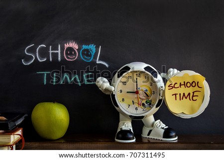 School time written with chalk on chalkboard, a clock and an apple in front of board.