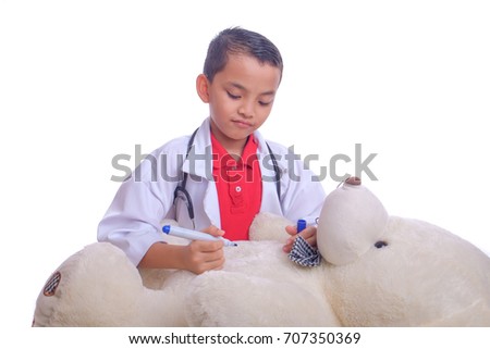 Cute asian boy with coat and stethoscope plays in doctor making operation teddy bear