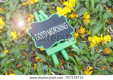 mini black board written good morning over flower and grass background