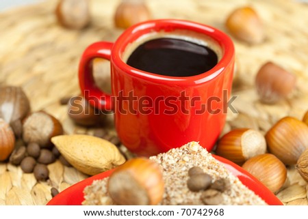 cake on a plate, nuts and a cup of coffee on a wicker mat