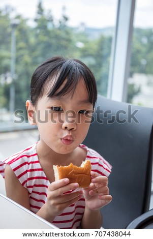 Asian Chinese little girl eating bread at indoor restaurant