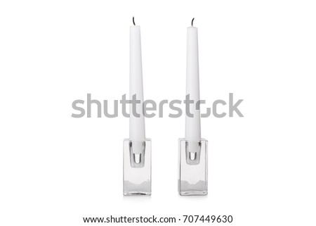 A close-up picture of two long white candles on transparent stands, isolated on a white background. Extinguished candles for a romantical date or beautiful dinner. Copy space.