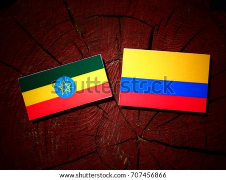Ethiopian flag with Colombian flag on a tree stump isolated