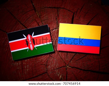 Kenyan flag with Colombian flag on a tree stump isolated