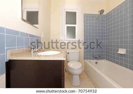 Nice new bathroom with blue tiles and brown cabinet under the sink