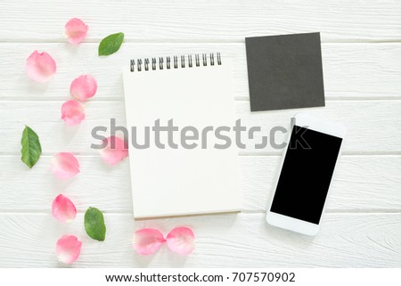 Blank notepad with smart phone and gift card on wooden background.view from above