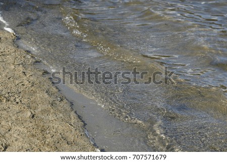 waves with brown sand on a lake