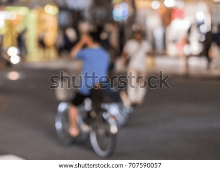 Blurred image of a person riding a bicycle at night in Shibuya street.