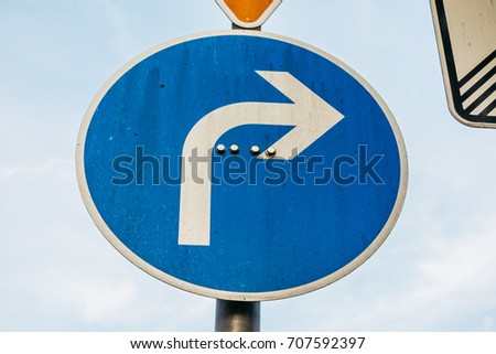 white arrow on blue traffic sign showing to the right