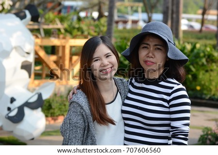 Asian sisters hugging and smiling in the park. thai