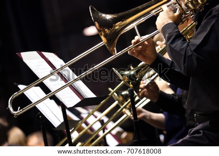 Trombones in the hands of musicians in the orchestra closeup Royalty-Free Stock Photo #707618008