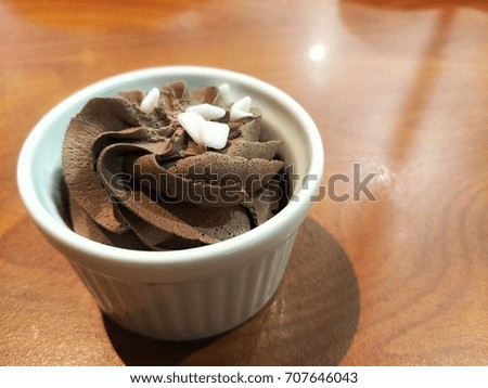 Soft cream in white ceramic cup on wooden table background.