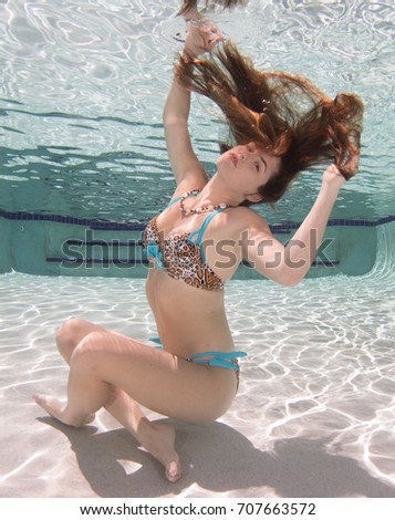 A model with long hair in a pool underwater.