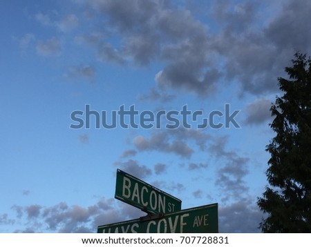 bacon heaven street sign at night with clouds tree