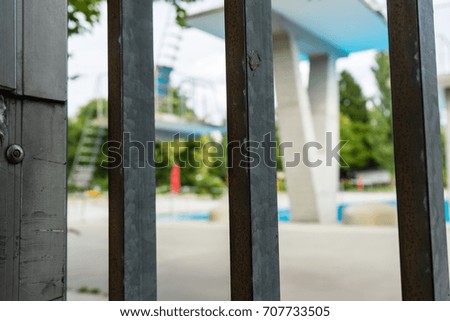 swimming bath seen through iron fence with jumping tower