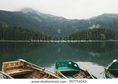 Landscape photo of beautiful mountain lake with boats or kayaks in foreground