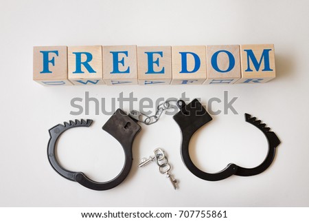 The word "Freedom" from wooden cubes and unbuttoned handcuffs