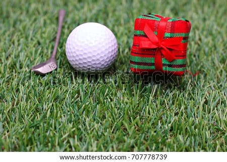 Golf ball with present and iron on green grass