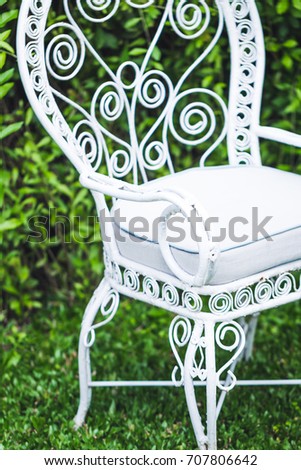 Old vintage furniture in garden with natural green background. White metal chair and table, old-fashioned european style