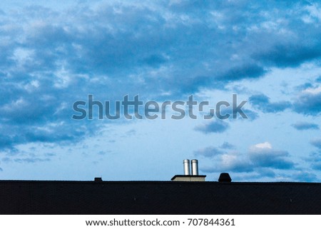 roof with metal chimney and evening sky with clouds blue hour