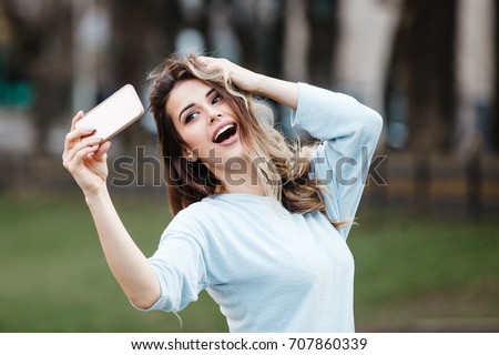 beautiful girl doing selfie on phone on the street