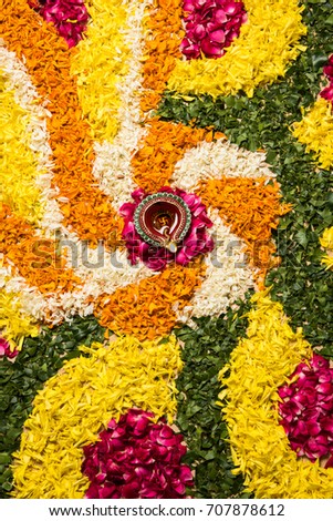 stock photo of flower rangoli for Diwali or pongal or onam made using marigold or zendu flowers and red rose petals over white background with diwali diya in the middle, selective focus
