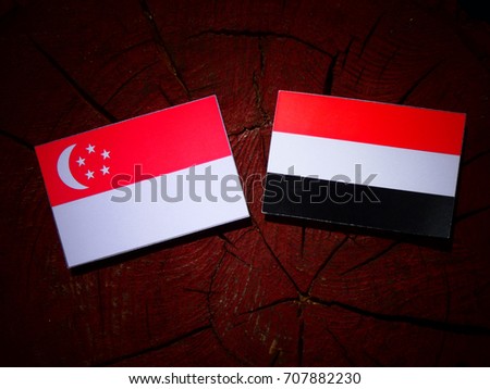 Singaporean flag with Yemeni flag on a tree stump isolated