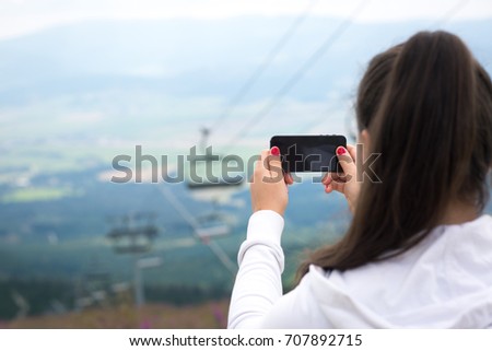 Young bruntte woman taking picture from view point of slovak tatras, landscape photo