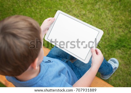Boy use tablet with isolated white screen for mockup. Child playing game, surfing or watching cartoon.