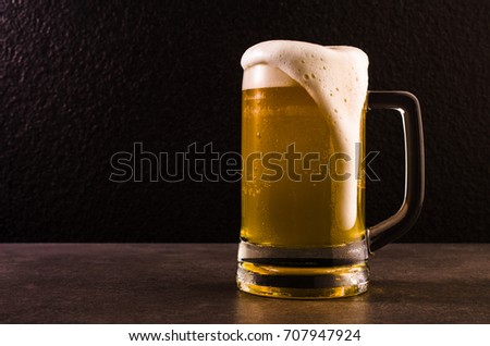 Beer in mug on concrete table near granite background.