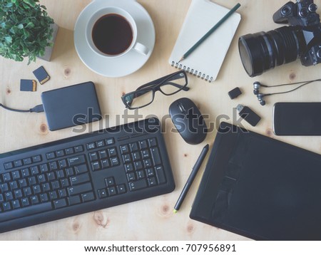 top view  work space of photographer or creative designer with digital camera, memory card, computer keyboard, graphic tablet, mouse, coffee cup on wooden table.