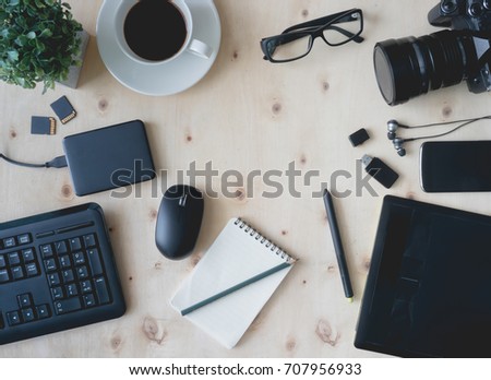 top view work space of photographer or creative designer with digital camera, memory card, computer keyboard, graphic tablet, mouse, coffee cup on wooden table.