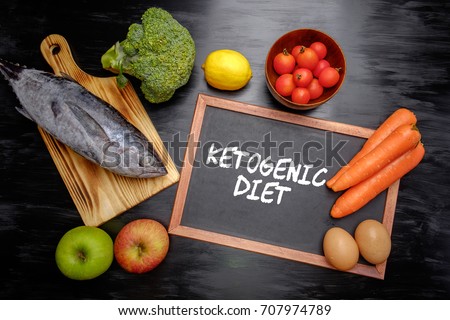 Ketogenic Diet (or Keto Diet) on chalkboard, health conceptual. Healthy fresh low carbohydrates food; egg, fish, lemon, tomatoes, apple, carrot and broccoli. Royalty-Free Stock Photo #707974789