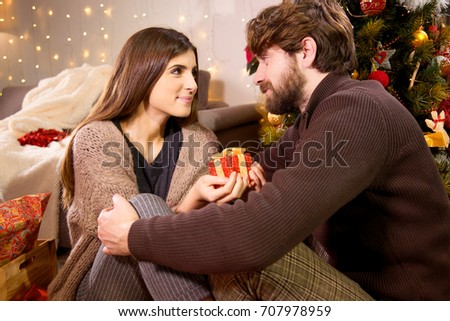 happy man with beard caressing girlfriend in front of christmas tree