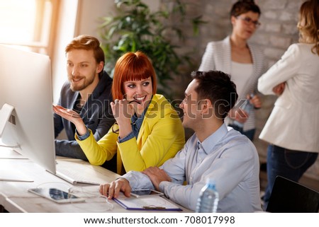 Group of young people working together on computer in office