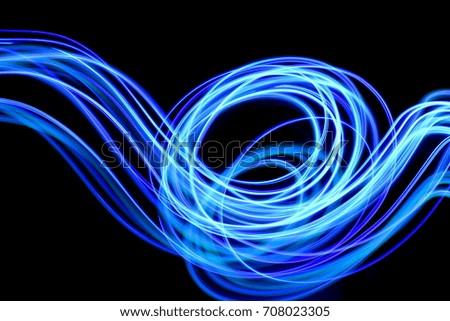 Blue light painting, long exposure photography, loop and swirl pattern against a black background