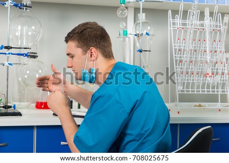 Male scientist in uniform smelling the test tube and making some research in a laboratory. Healthcare and biotechnology concept
