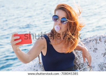 Young woman taking a selfie by the sea