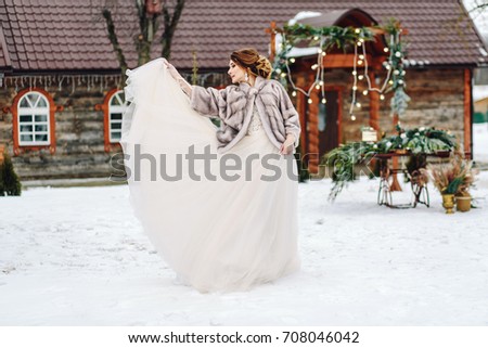 Young bride in gorgeous wedding dress posing outdoors. Winter wedding.