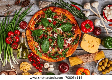 Decoration from pizza and vegetables. Traditional italian food, wooden background.