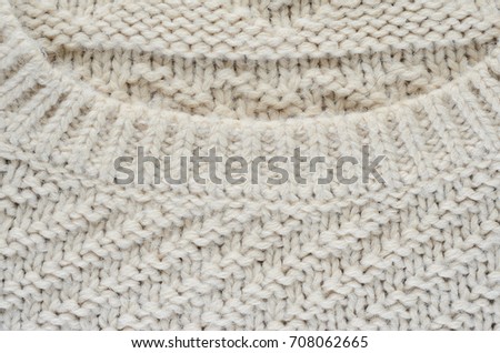 Texture of a beige knitted sweater. Element of a collar on a knitted product close-up
