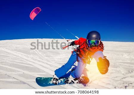 Snowboarder with a kite on fresh snow in the winter in the tundra of Russia against a clear blue sky. Teriberka, Kola Peninsula, Russia. Concept of winter sports snowkite. Royalty-Free Stock Photo #708064198