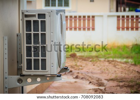 New Air conditioner compressor installed outside the house on the white wall with steel beam supported.  Royalty-Free Stock Photo #708092083