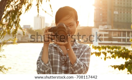 Vietnamese girl photographer takes pictures of nature in the city center at sunset