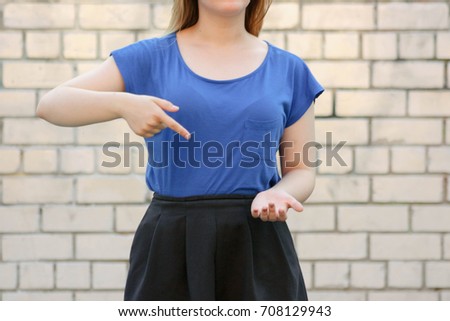 Reflection and choice concept. Girl in blue against a white brick wall. Photo for your design. To point one's finger at